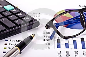 Financial tools, calculator, pen and spectacles over a report