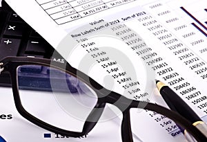 Financial tools, pen pointing over a report and spectacles