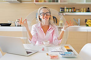 Financially free and calm housewife sitting in kitchen