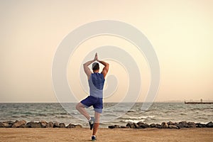 Find balance and unite with nature. Yoga practice helps find harmony and balance. Man practicing yoga sea beach