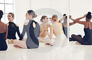 Find the way to be yourself in your art. a group of young ballerinas doing their hair before rehearsal in a studio.