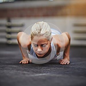 Find the will inside yourself. a young woman doing pushups in a gym.