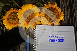 Find your purpose inspirational words on notebook paper with yellow flowers on classic tablecloth background