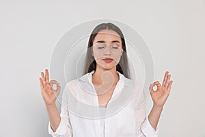 Find zen. Beautiful young woman meditating on white background