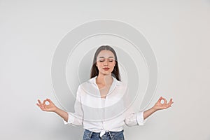 Find zen. Beautiful young woman meditating on white background