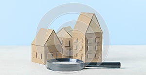 Finding or choosing the best home. Magnifying glass and cardboard miniature houses. Sale or rental of housing