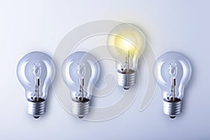 Finding innovative solutions and creative ideas, being unique, thinking different concept. Group of light bulbs with one glowing photo