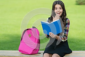 Finding inspiration in reading. Surprised child read book sitting on park bench. Inspiration concept. School library