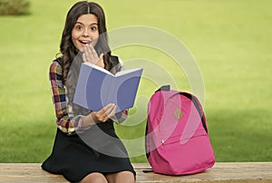 Finding inspiration in reading. Surprised child read book sitting on park bench. Inspiration concept. School library