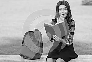 Finding inspiration in reading. Surprised child read book sitting on park bench. Inspiration concept. School library