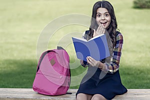 Finding inspiration in reading. Surprised child read book sitting on park bench. Inspiration concept. School library