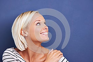 Finding reasons to smile. Studio shot of an attractive young woman looking up at copyspace.