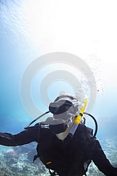 Finding recreation beneath the waves. Young woman scuba diving in the beautiful ocean with the bright sun shining