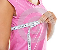 Finding the right bra size is important. a woman measuring her bust with a measuring tape against a white background.