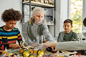 Finding solutions. Three kids building robots and vehicles at robotics lesson. Smart children and STEM education.