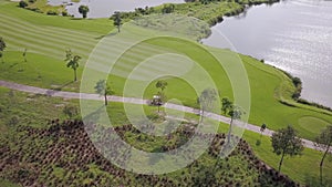 Fine aerial view of golf cart driving along track to next hole, elite golf club
