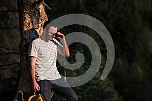 Fine art portrait of a hipster man wearing sunglasses in a forest.