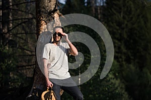 Fine art portrait of a hipster man wearing sunglasses in a forest.