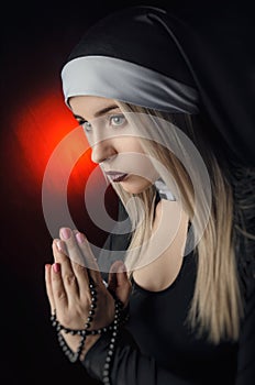 Fine art portrait of a novice nun in deep prayer with rosary