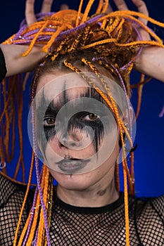 Fine art portrait of young woman with horror stage make up painted on face and dreadlocks hairstyle