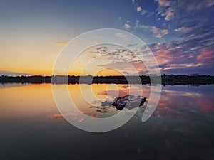 Fine art shot with an old, rusty catamaran frame forgotten on the pond. Scenery landscape, peaceful sunset sky background with