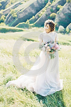 Fine art wedding photography. Beautiful bride with bouquet and dress with train in nature