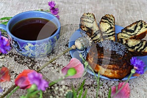 A fine breakfast, a mug of tea, fresh rolls with poppy seeds and poppy flowers