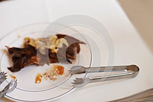 Fine dining, meat and food on plate in restaurant for nutrition, dinner or lunch at table with tongs. Protein, steak and