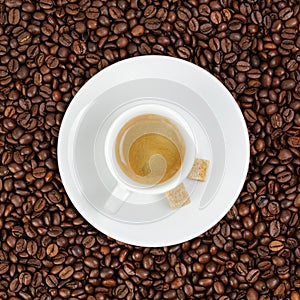 Fine espresso in cup on coffee beans