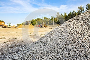 A fine gray graphite gravel is piled high on the background of machinery and wood. Road repair.