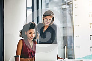 Fine-tuning their latest plans. two businesswomen working together on a laptop in an office.