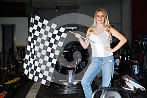 Fine woman with race flag standing near car