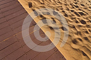 Fine yellow warm sand and wooden floor. Contrast of two materials. Rich textured shot