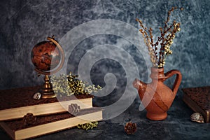 Fineart concept shot. Stilllife with rustic books  with flowers and globe on grey backgrouns