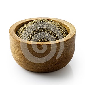 Finely ground black pepper in dark wood bowl.