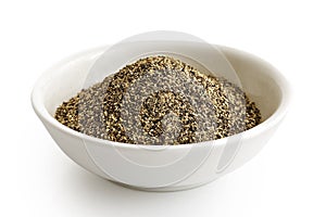 Finely ground black pepper in white ceramic bowl isolated on white.