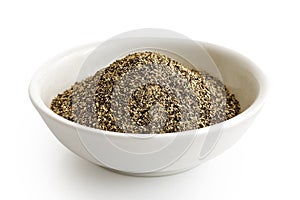 Finely ground black pepper in white ceramic bowl isolated on white. photo