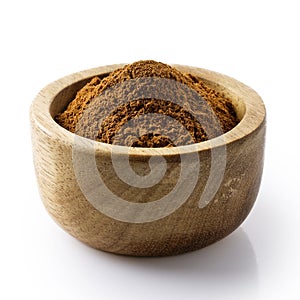 Finely ground cinnamon in dark wood bowl. photo