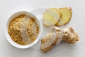 Finely ground dry ginger in white ceramic bowl on white