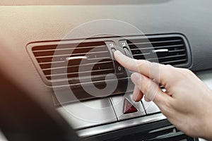 Finger adjusting air outlet deflector of HVAC on dashboard in car photo