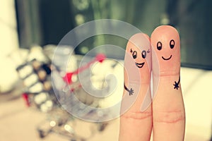 Finger art of a Happy couple. A man and a woman hug on the background shopping cart.