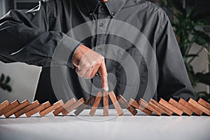 Finger of businessman pointing one wooden to stopping domino effect stopped