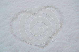 Finger-drawn heart on the snow-covered windshield of a car.Valentine's Day concept.Creative Valentine's Day background.