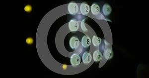 Finger entering combination code on a keypad with illuminating buttons setting security system on shot on red