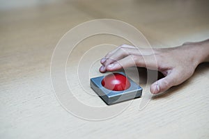 finger extended Press the red button on wood table.