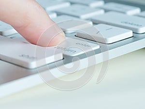 Finger of female is pressing enter key of a computer keyboard