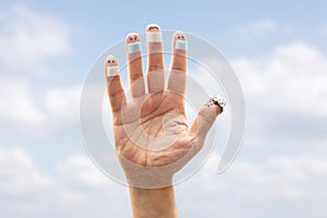 Finger figures with face masks and thumb with a tin foil hat, sky background