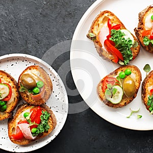 Finger food. Appetizing crostini with baked capsicum, green peas, bacon, kale and lettuce as a festive snack. Top view,