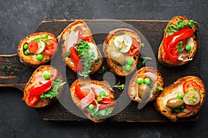 Finger food. Appetizing crostini with baked capsicum, green peas, bacon, kale and lettuce as a festive snack. Top view,