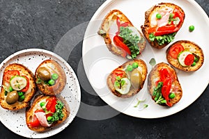 Finger food. Appetizing crostini with baked capsicum, green peas, bacon, kale and lettuce as a festive snack. Top view,